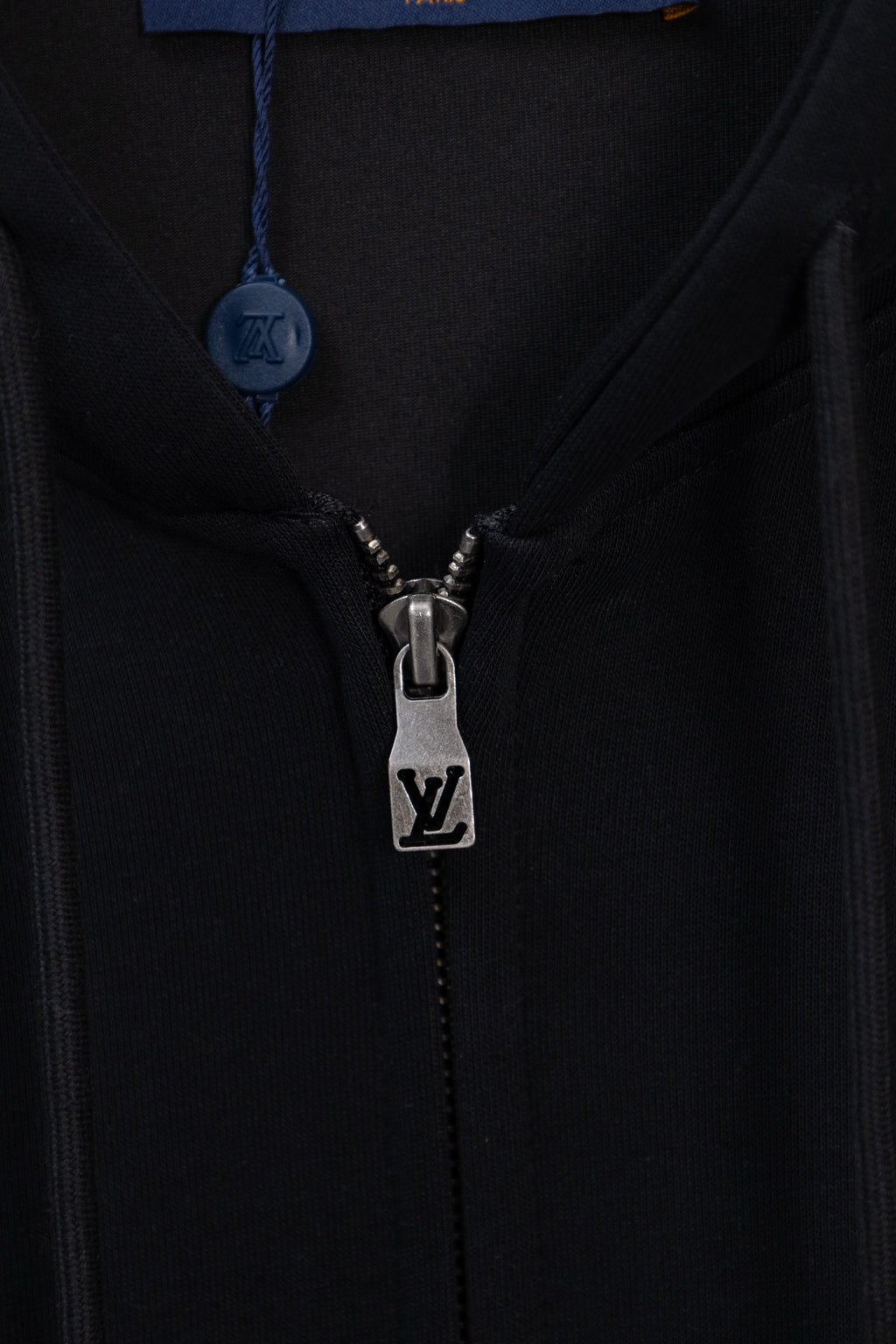 Dark navy hoodie close-up of front zipper and LV logo on metal pull