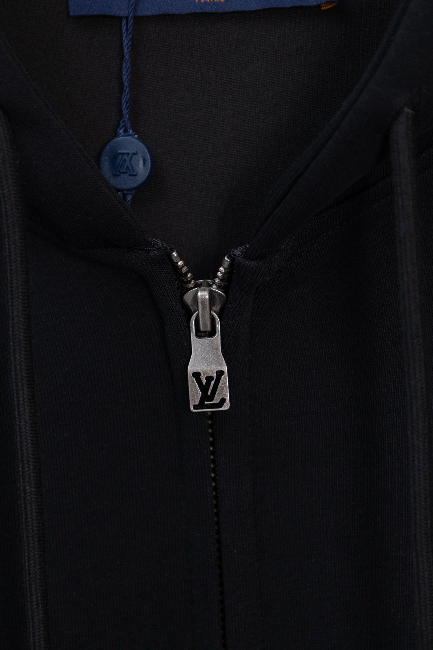 Dark navy hoodie close-up of front zipper and LV logo on metal pull