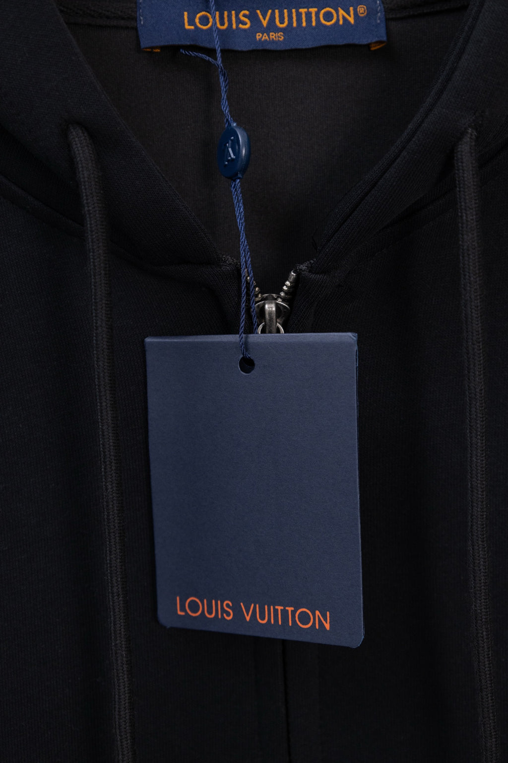 Dark navy hoodie with hood drawcords and hanging LV logo tag at zipper