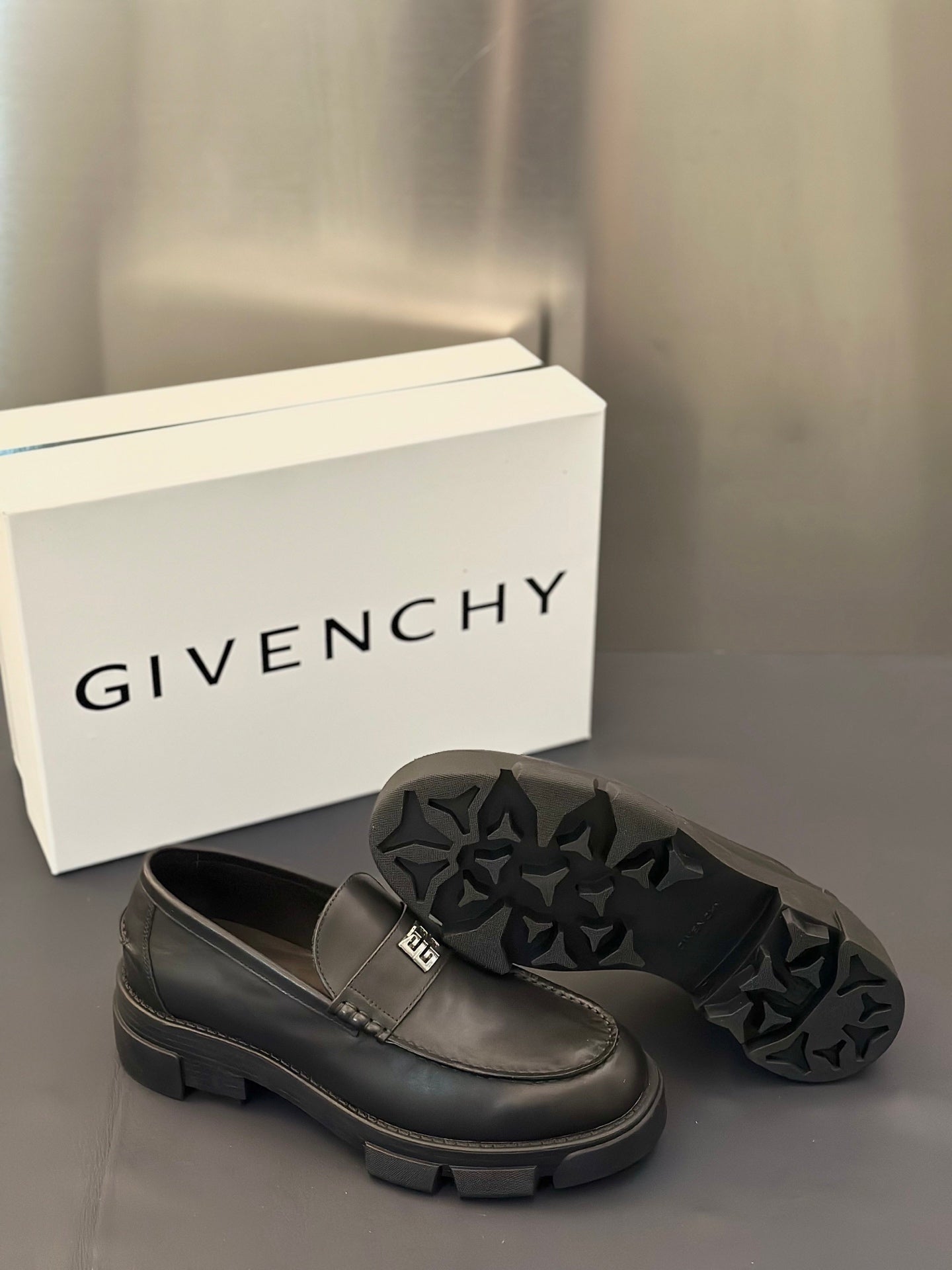 Dark leather loafer with square logo buckle and textured star-pattern outsole