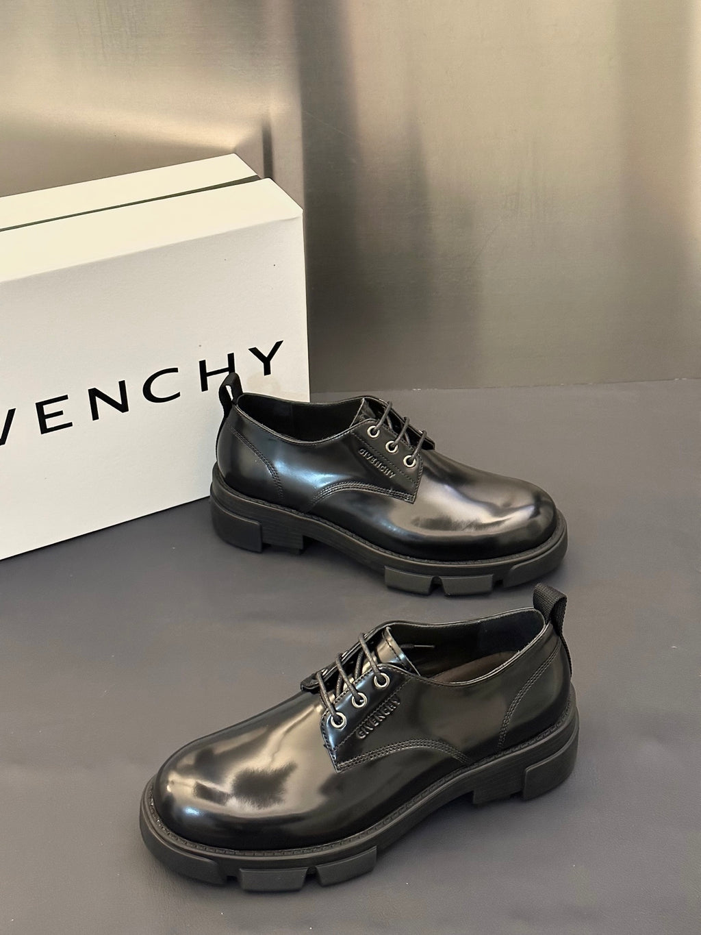 Black leather lace-up derby shoes with eyelets and chunky tread sole