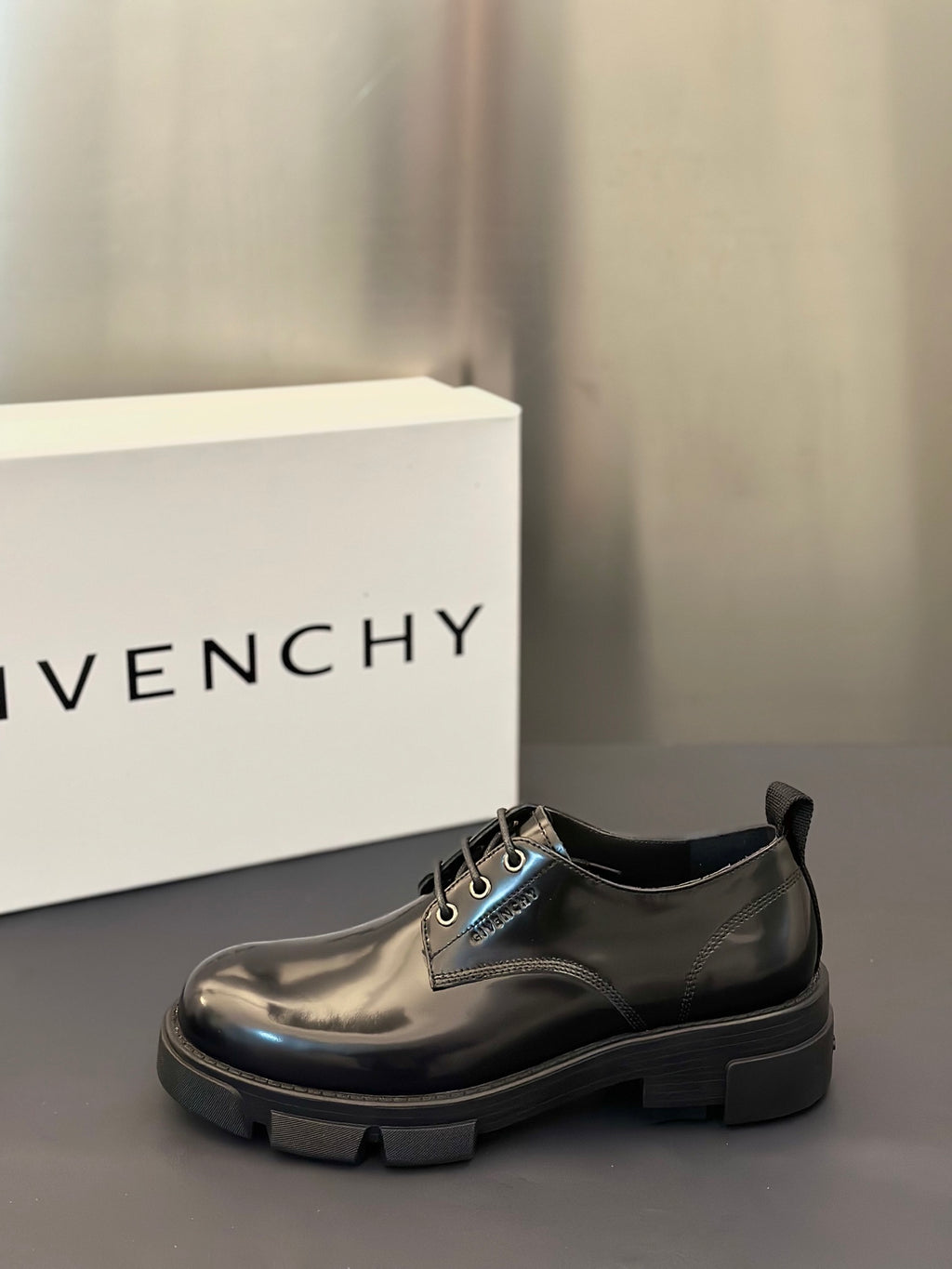 Black leather lace-up derby shoe with metal eyelets and lace-detail tongue