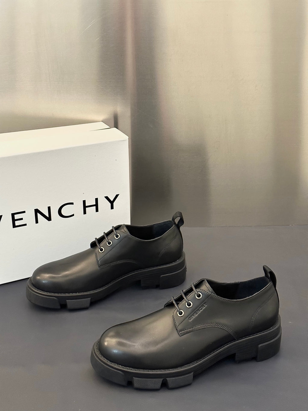 Black leather lace-up shoes with low collar, metal eyelets, and thick tread sole