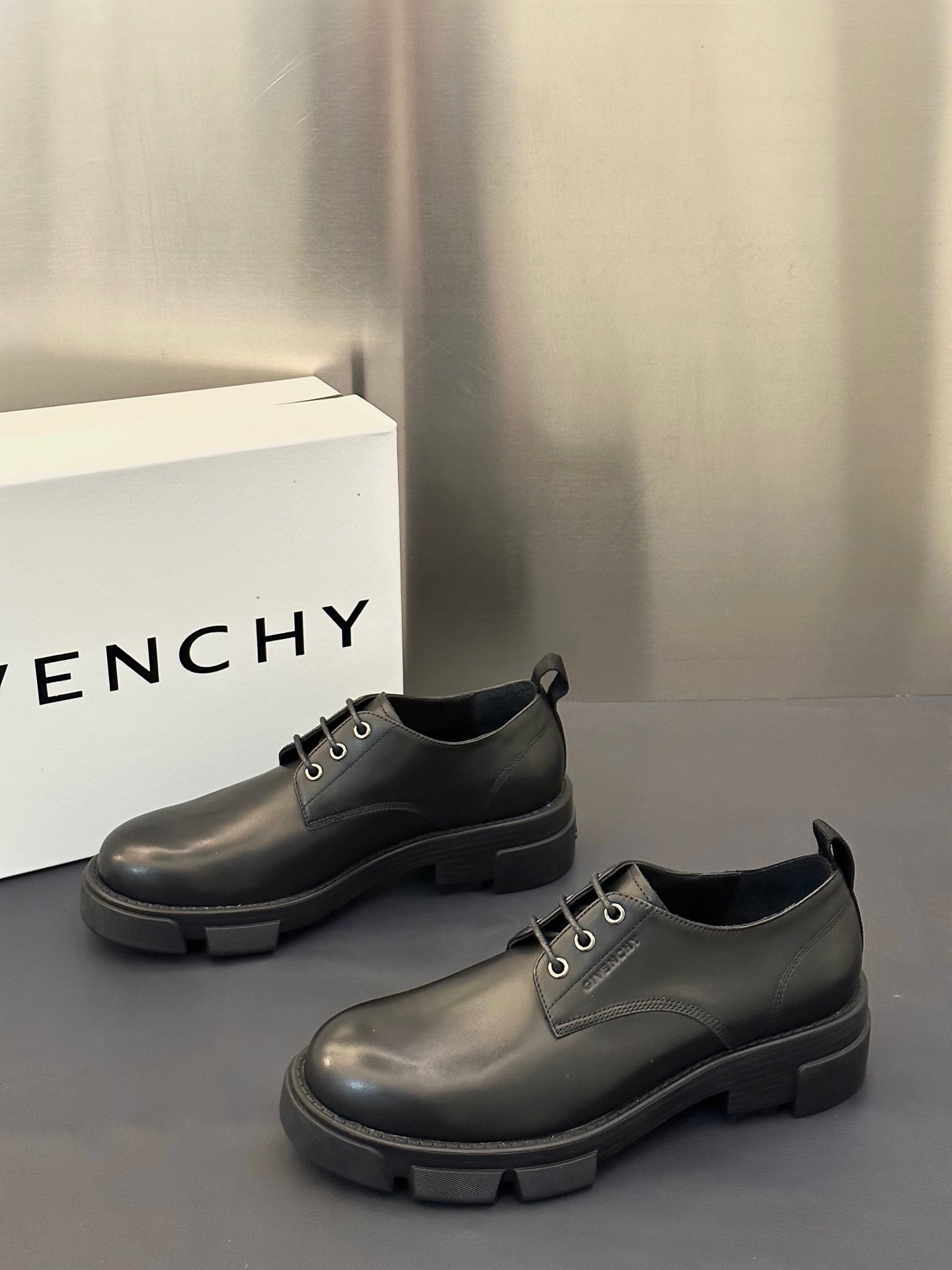 Black leather lace-up shoes with low collar, metal eyelets, and thick tread sole