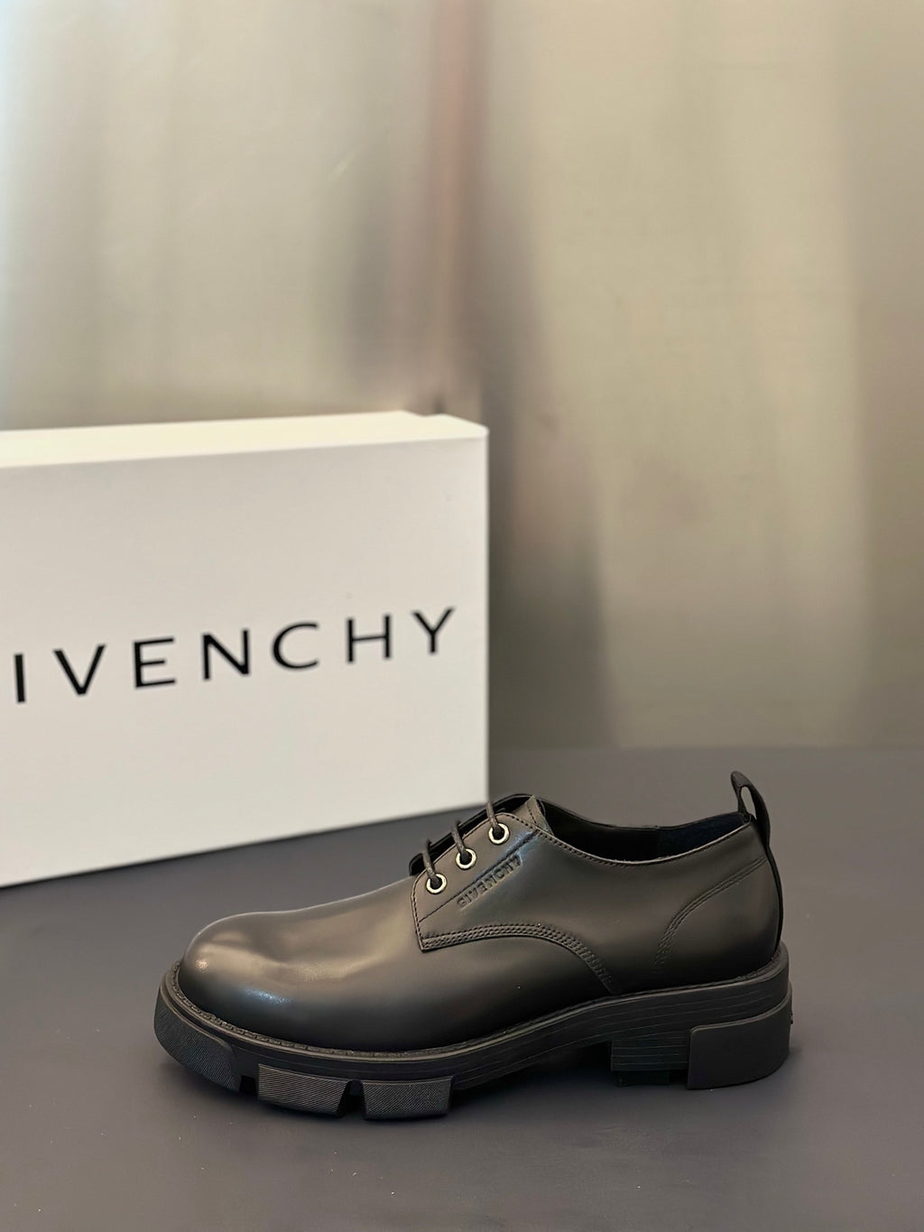 Dark leather lace-up shoe with thick sole, side view.