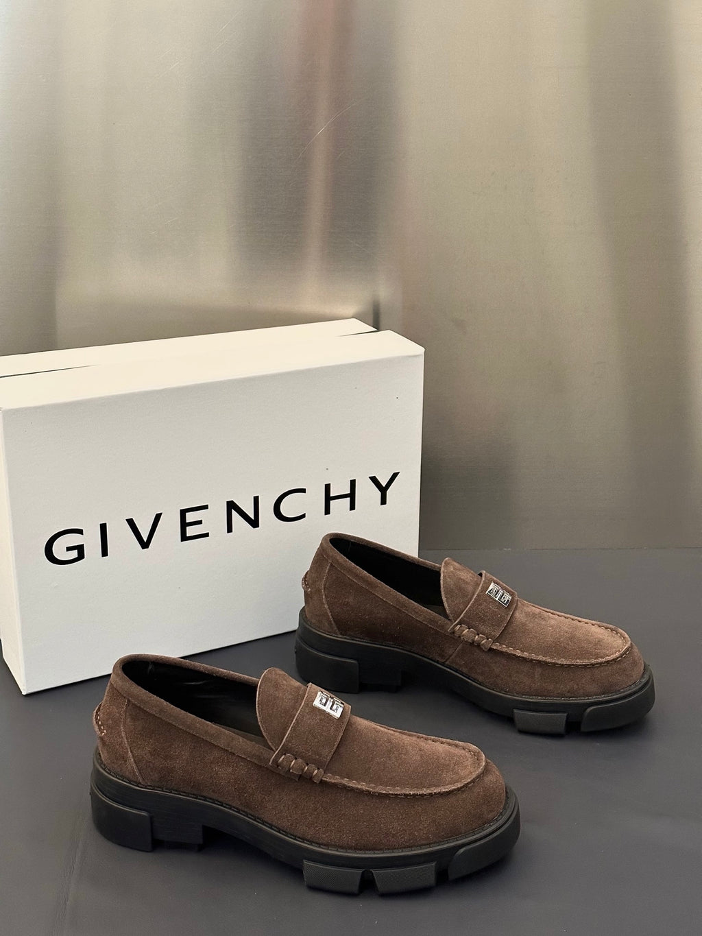 Brown suede loafers, side view, with logo plaque strap and chunky dark sole