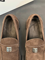 Close-up of brown suede loafers with logo plaque on strap and soft lining