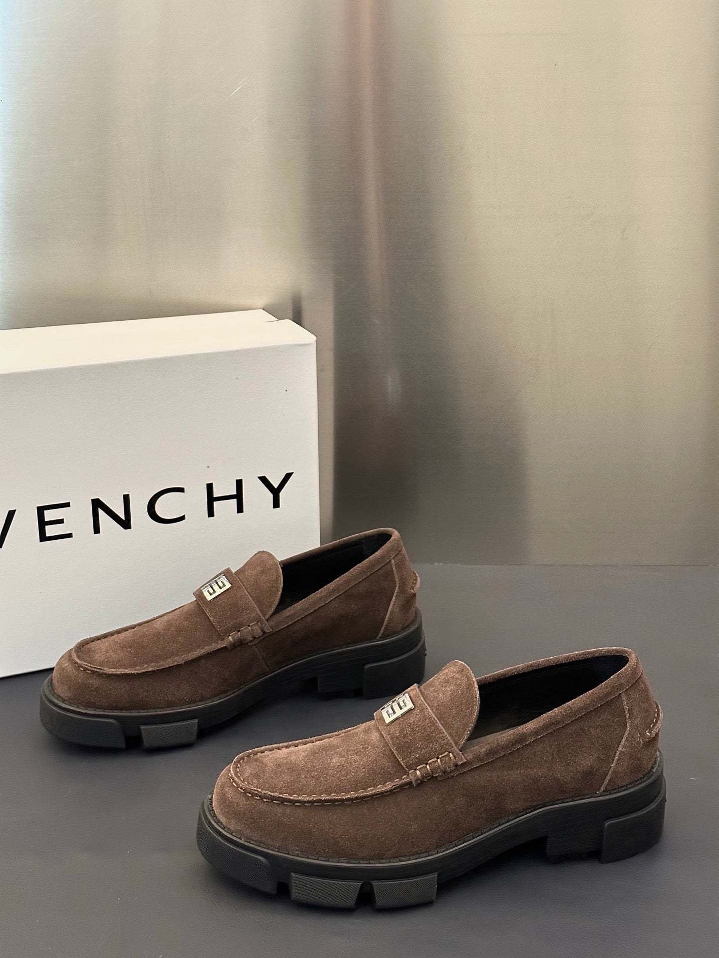 Brown suede loafers with logo plaque strap and dark treaded sole, pair view