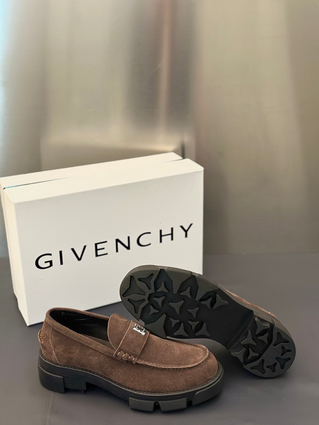 Brown suede loafers with logo plaque strap; outsole with textured tread shown