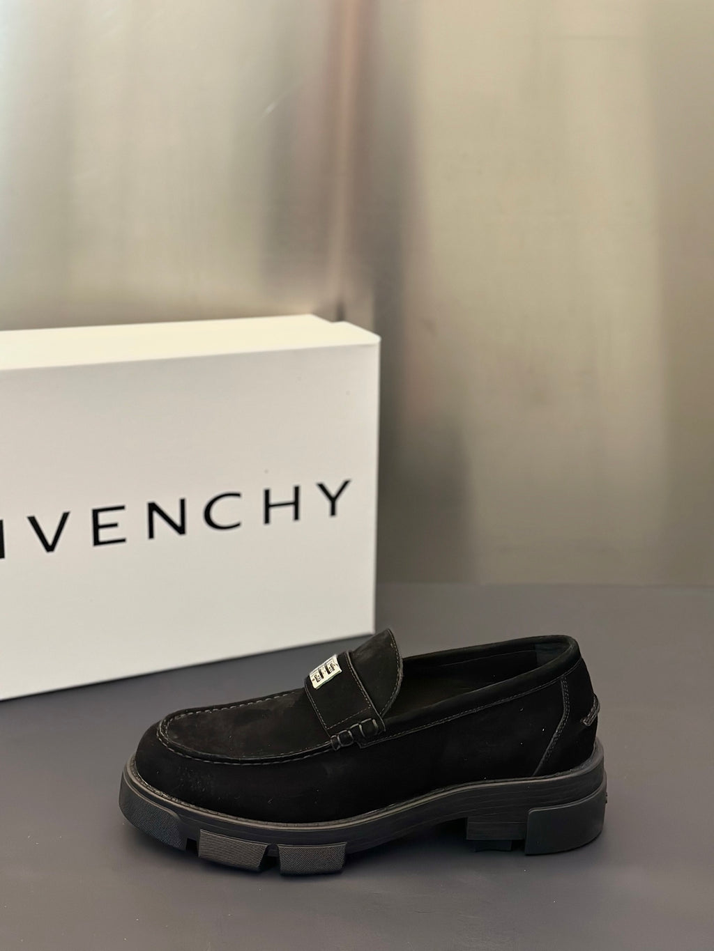 Black slip-on loafers with logo strap detail and chunky rubber sole, side view