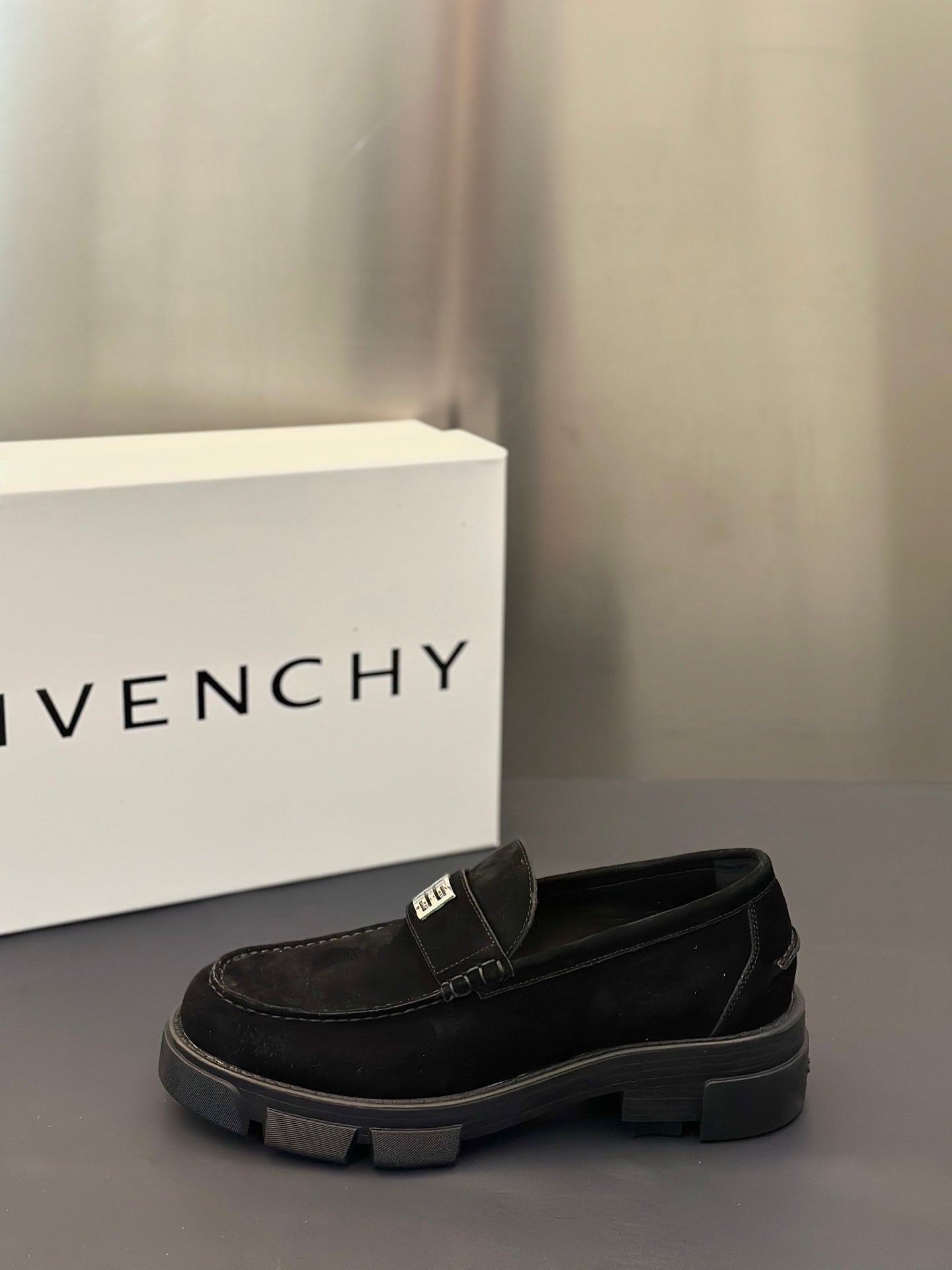 Black slip-on loafers with logo strap detail and chunky rubber sole, side view