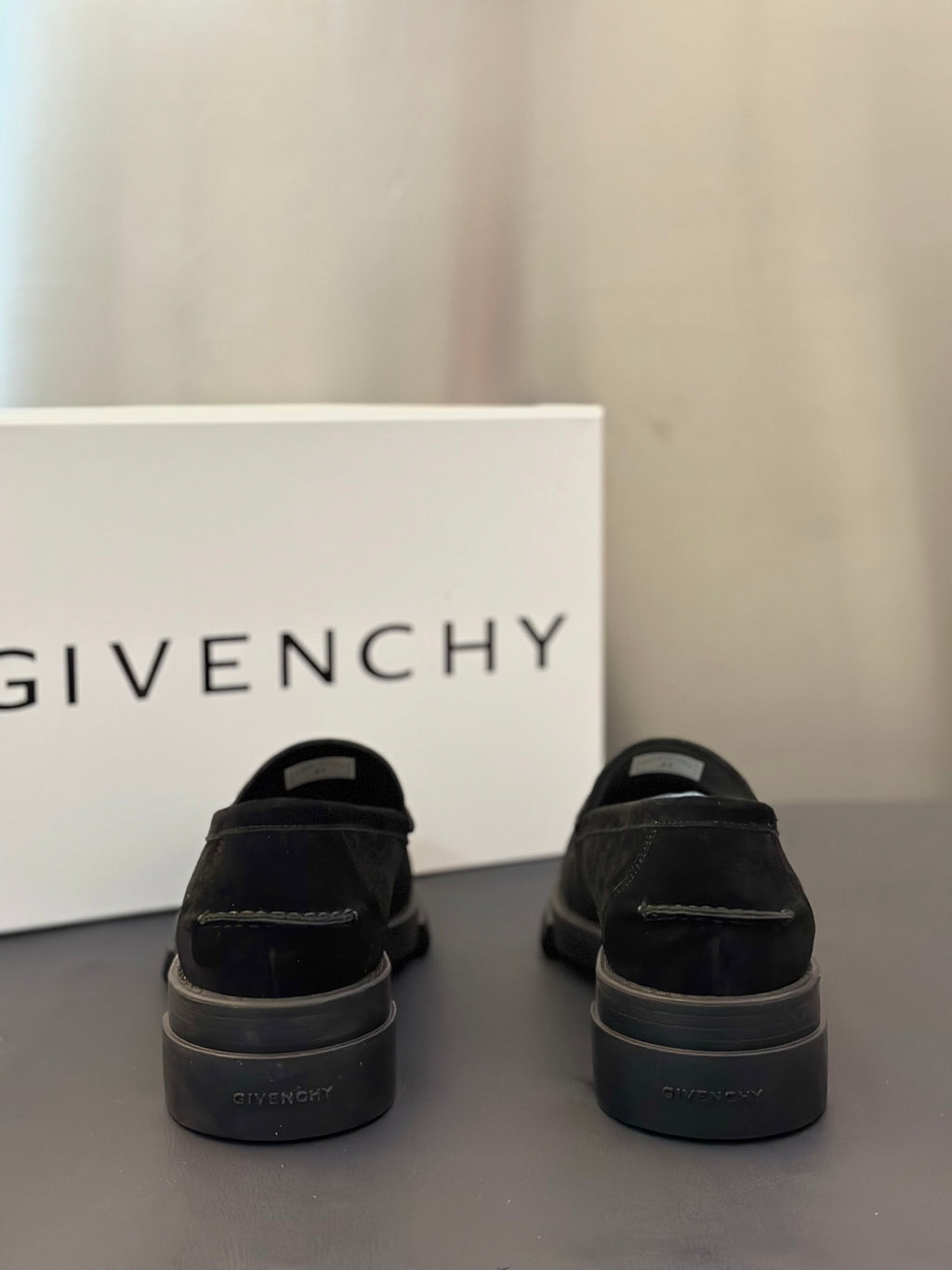 Black loafers from heel view with rear branding and chunky sole, pair on surface