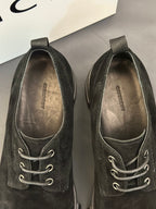 Black lace-up shoes viewed from toe and tongue; eyelets and laces visible.