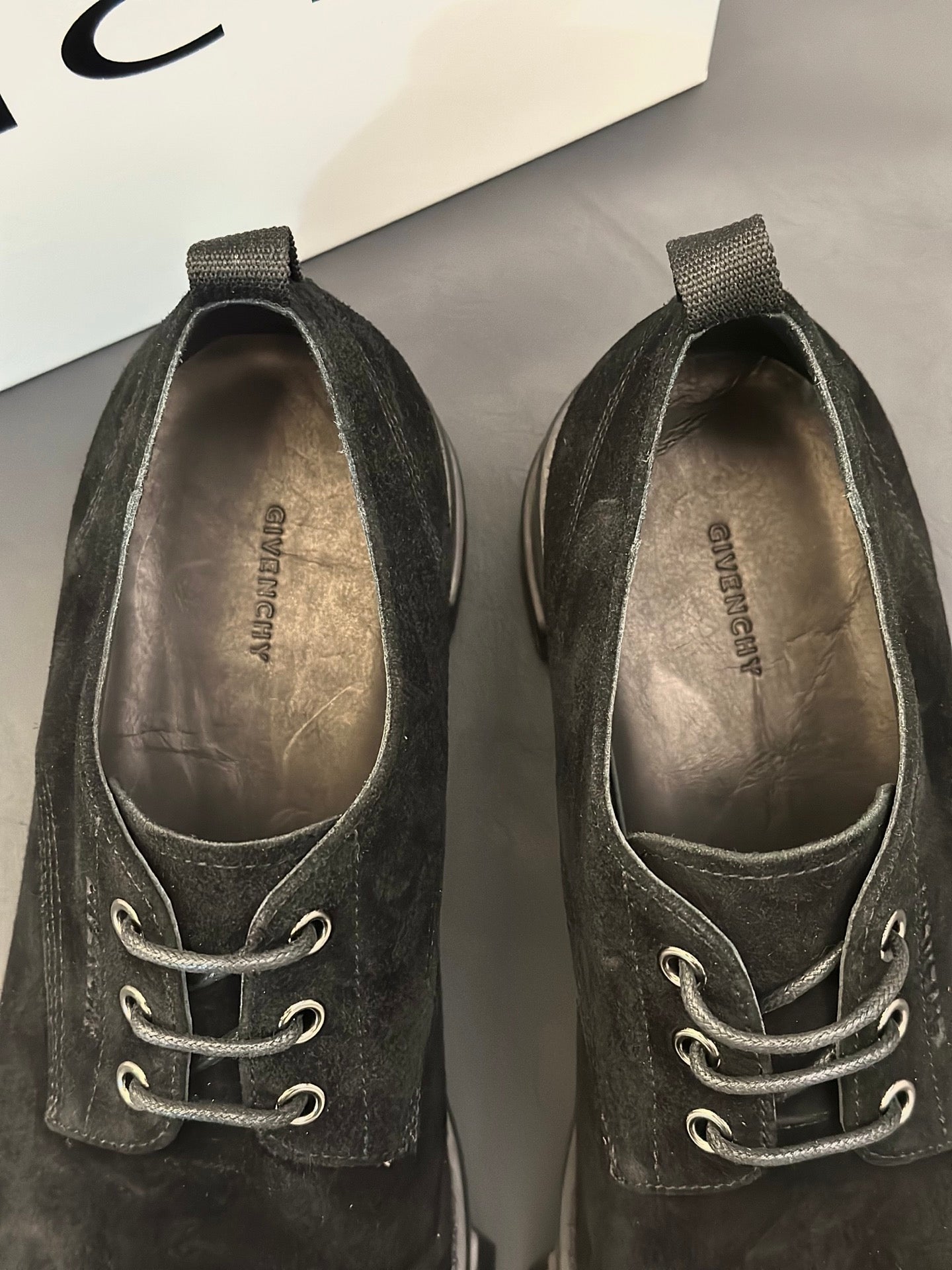 Black lace-up shoes viewed from toe and tongue; eyelets and laces visible.