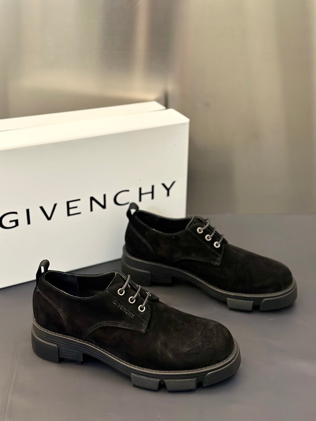 Pair of black lace-up oxford shoes with metal eyelets and rubber tread sole.