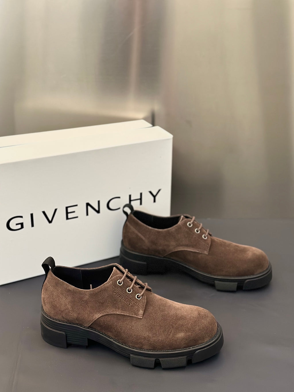 Brown suede lace-up shoes with thin metal eyelets and chunky dark rubber sole