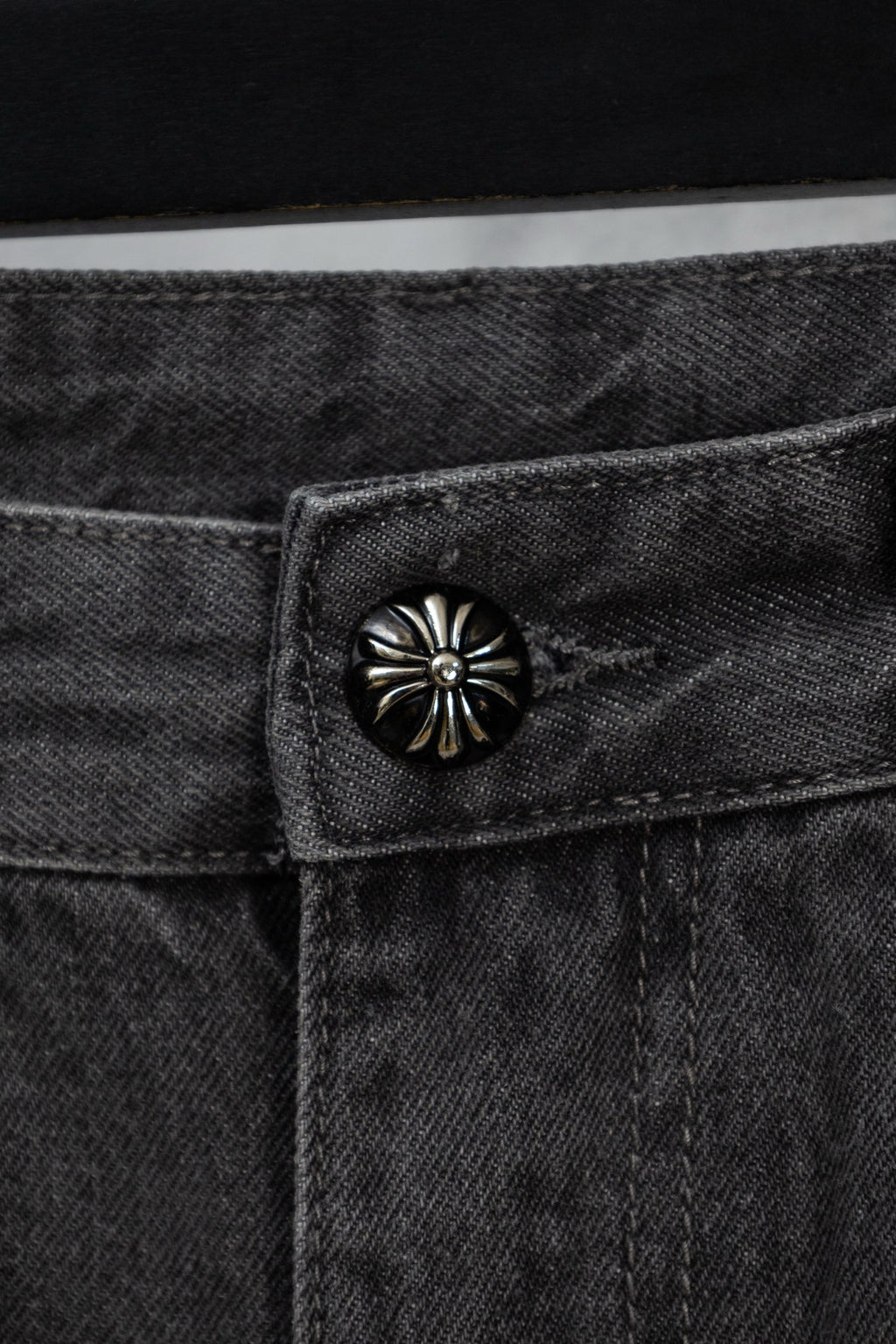 Dark denim pants with round metal button at the waistband