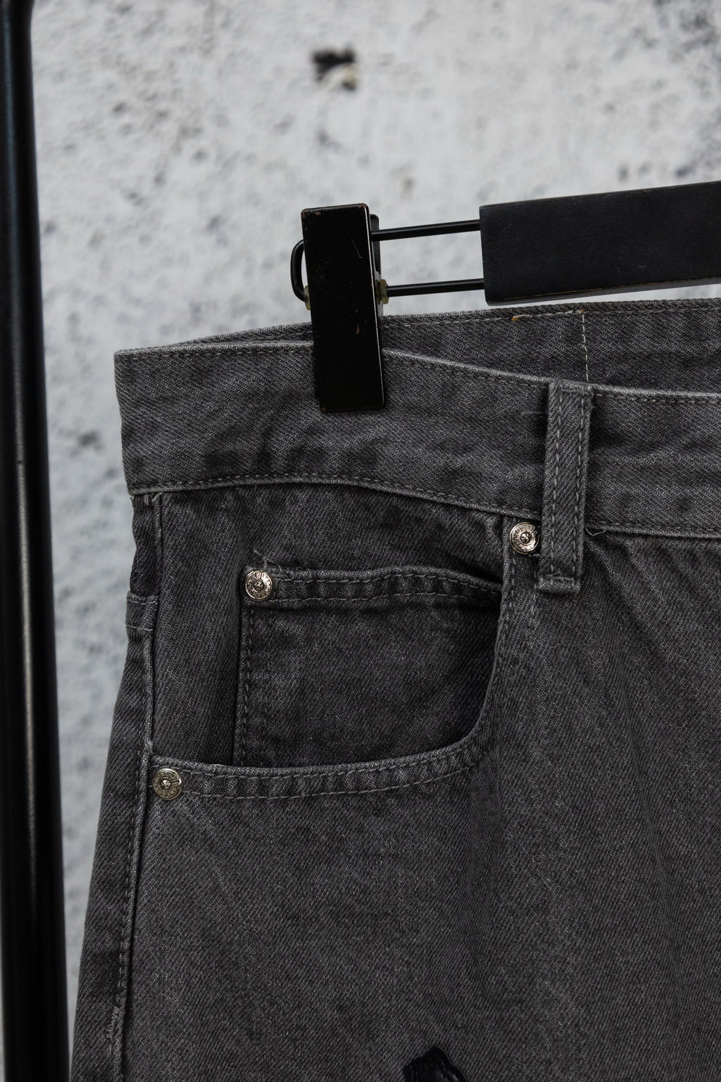 Dark denim pants with buttoned front pocket and rivet details