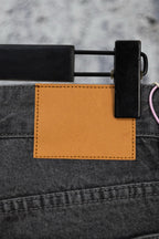 Dark gray denim pants with tan side pocket panel and black accessory holder