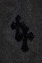 Black cross appliqué detail on dark gray denim