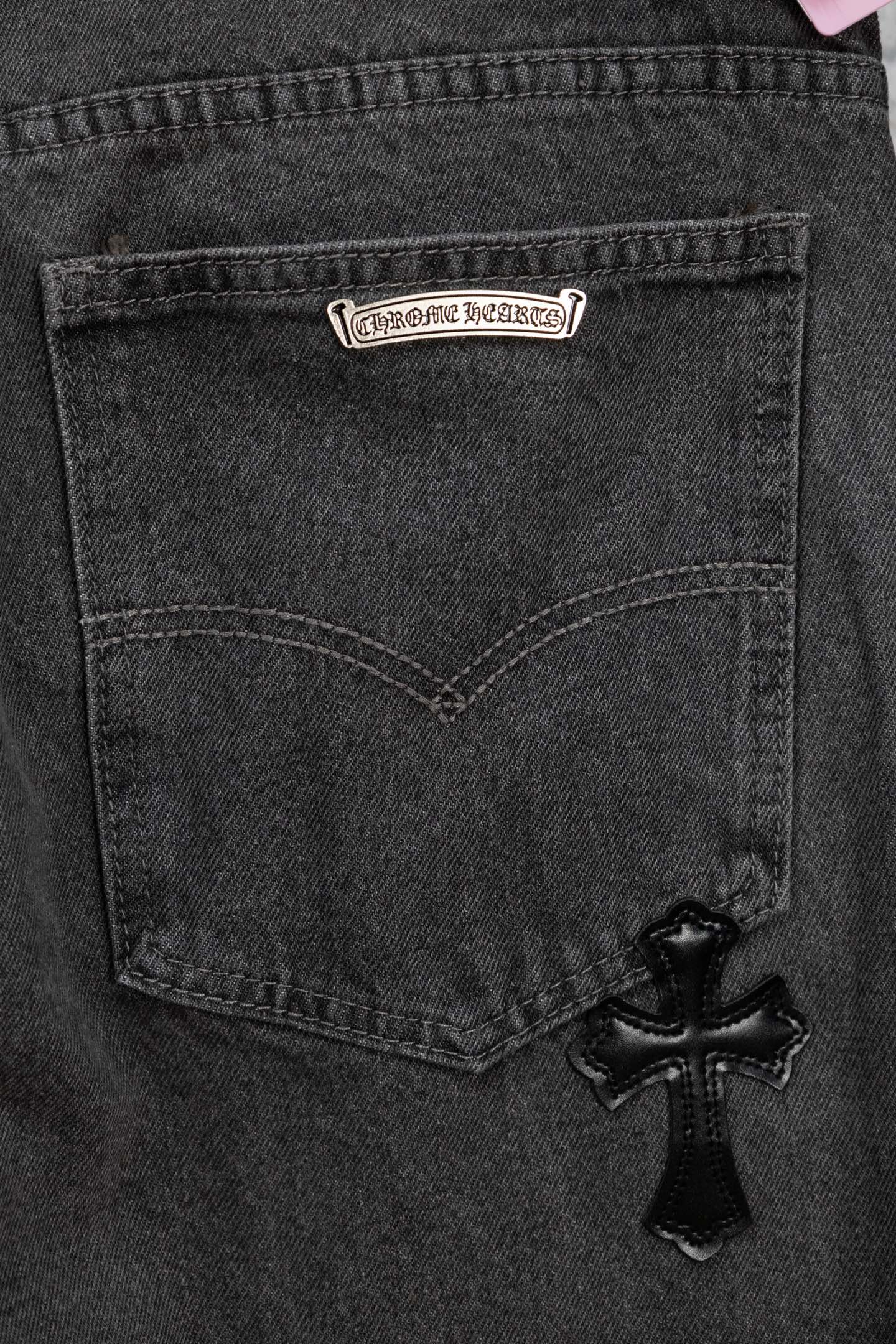 Dark gray denim pocket with heart-shaped stitching and black cross appliqué