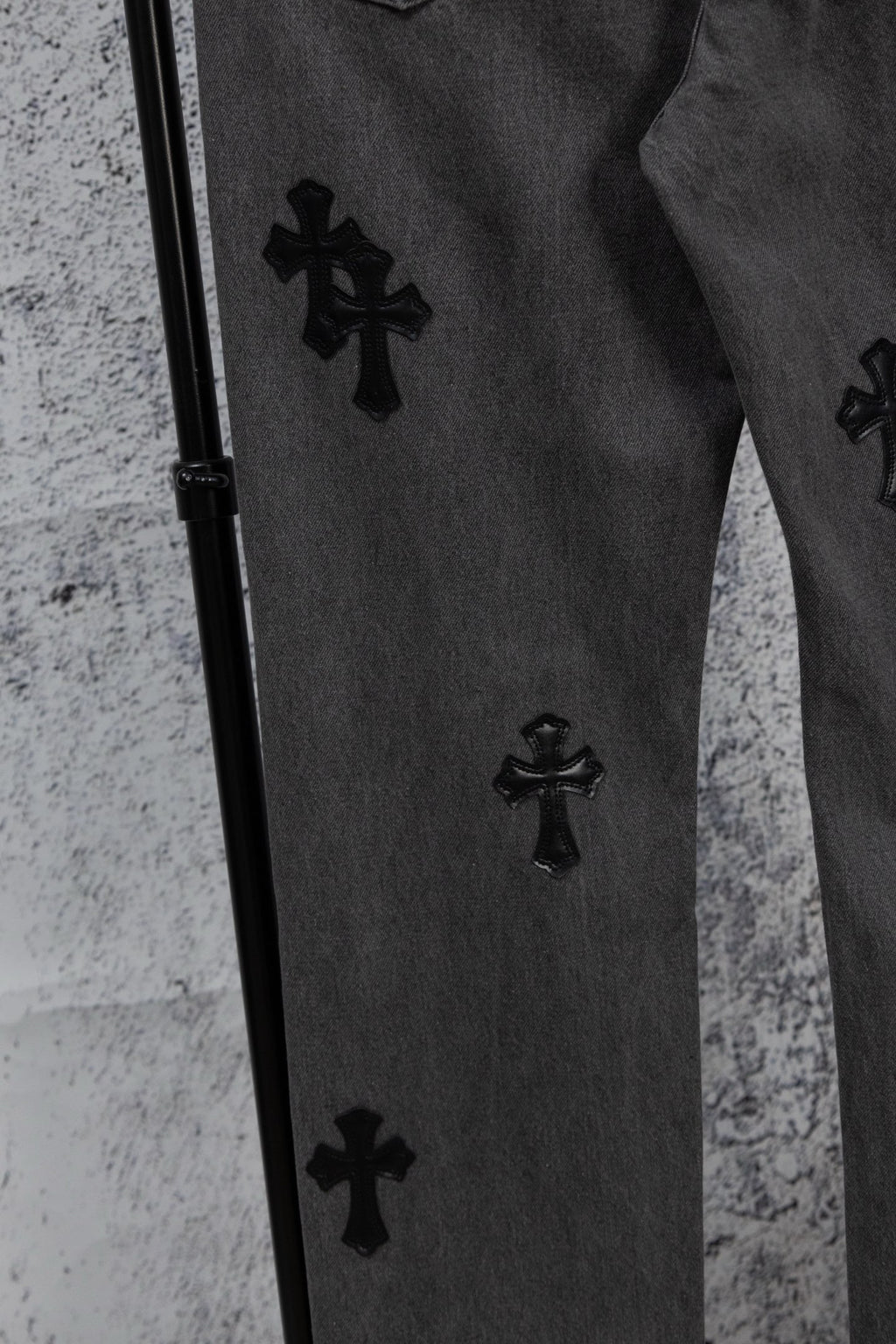 Dark denim pants with black cross patches along the side seam