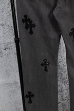 Dark denim pants with black cross patches along the side seam