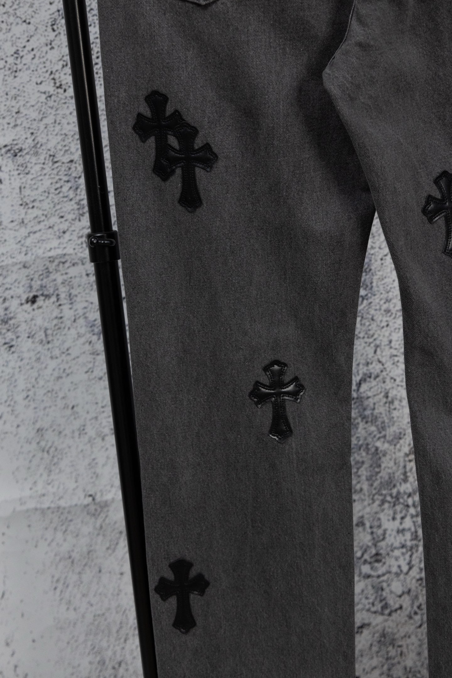 Dark denim pants with black cross patches along the side seam