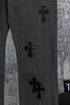 Dark denim pants with black cross embroidery on the leg