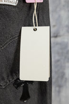 Dark denim pants with belt loops and hang tag, inner pocket stitching visible