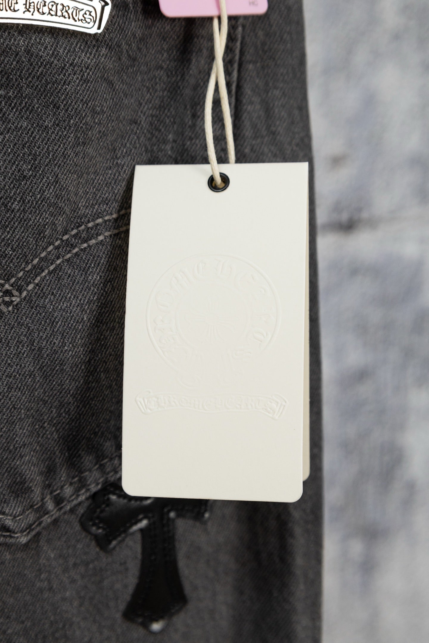 Dark denim pants with belt loops and hang tag, inner pocket stitching visible