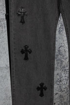 Dark denim pants with multiple black cross embroideries on the leg