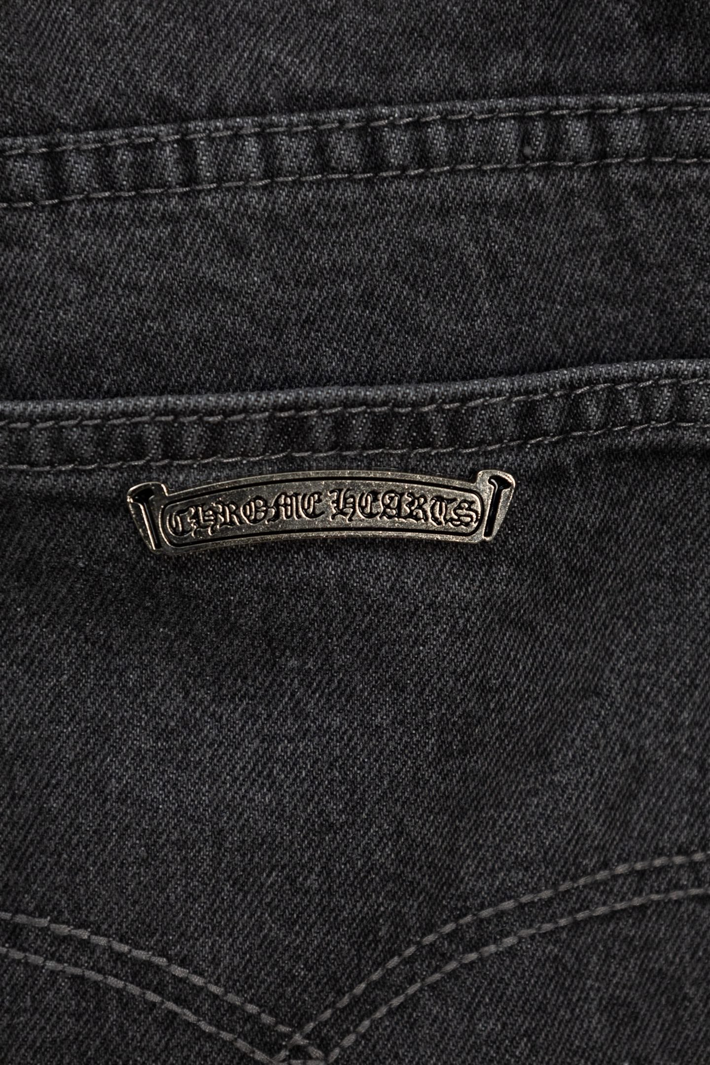 Dark denim pants with embroidered logo patch on front pocket