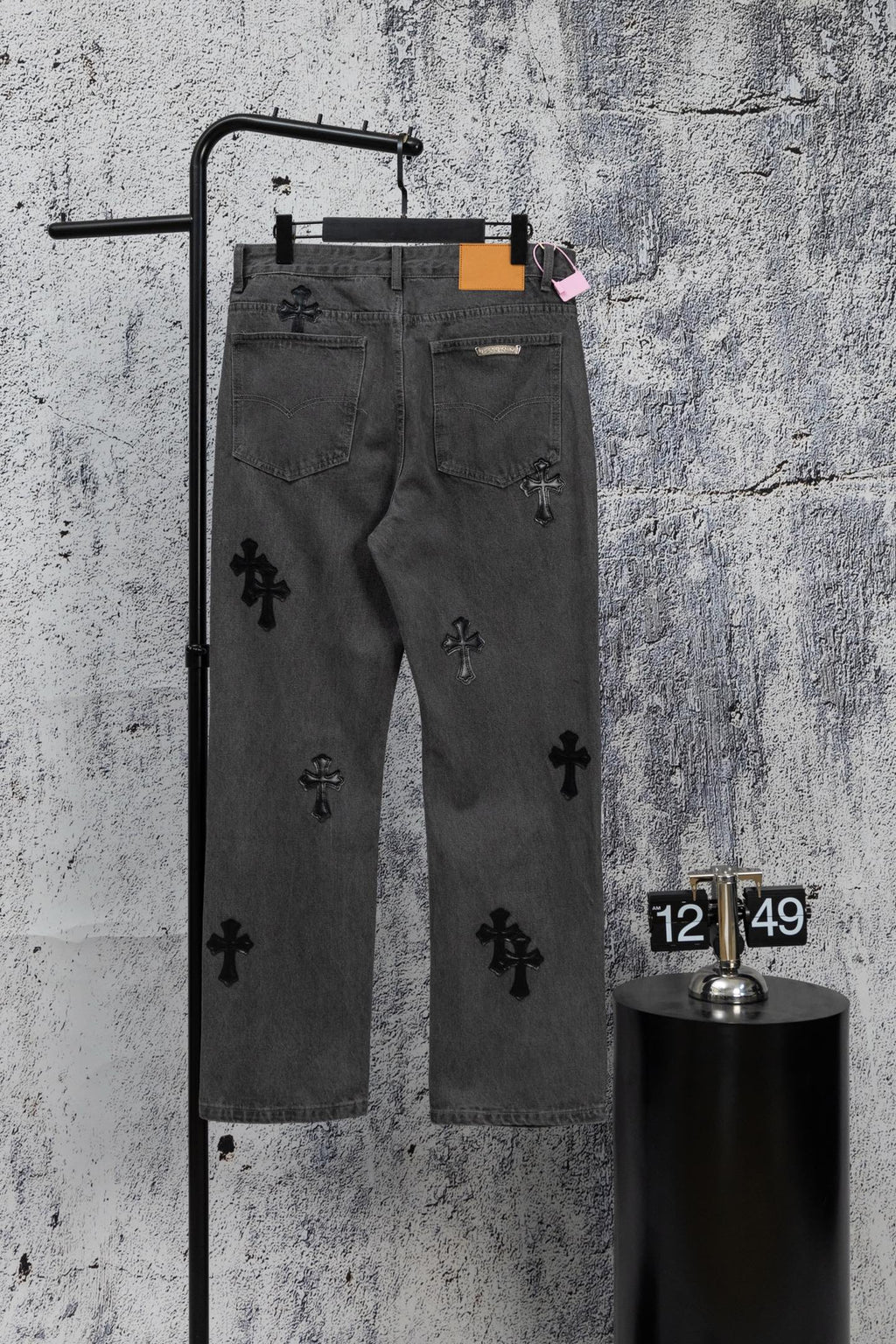 Dark gray denim pants with scattered black cross appliques and belt loops