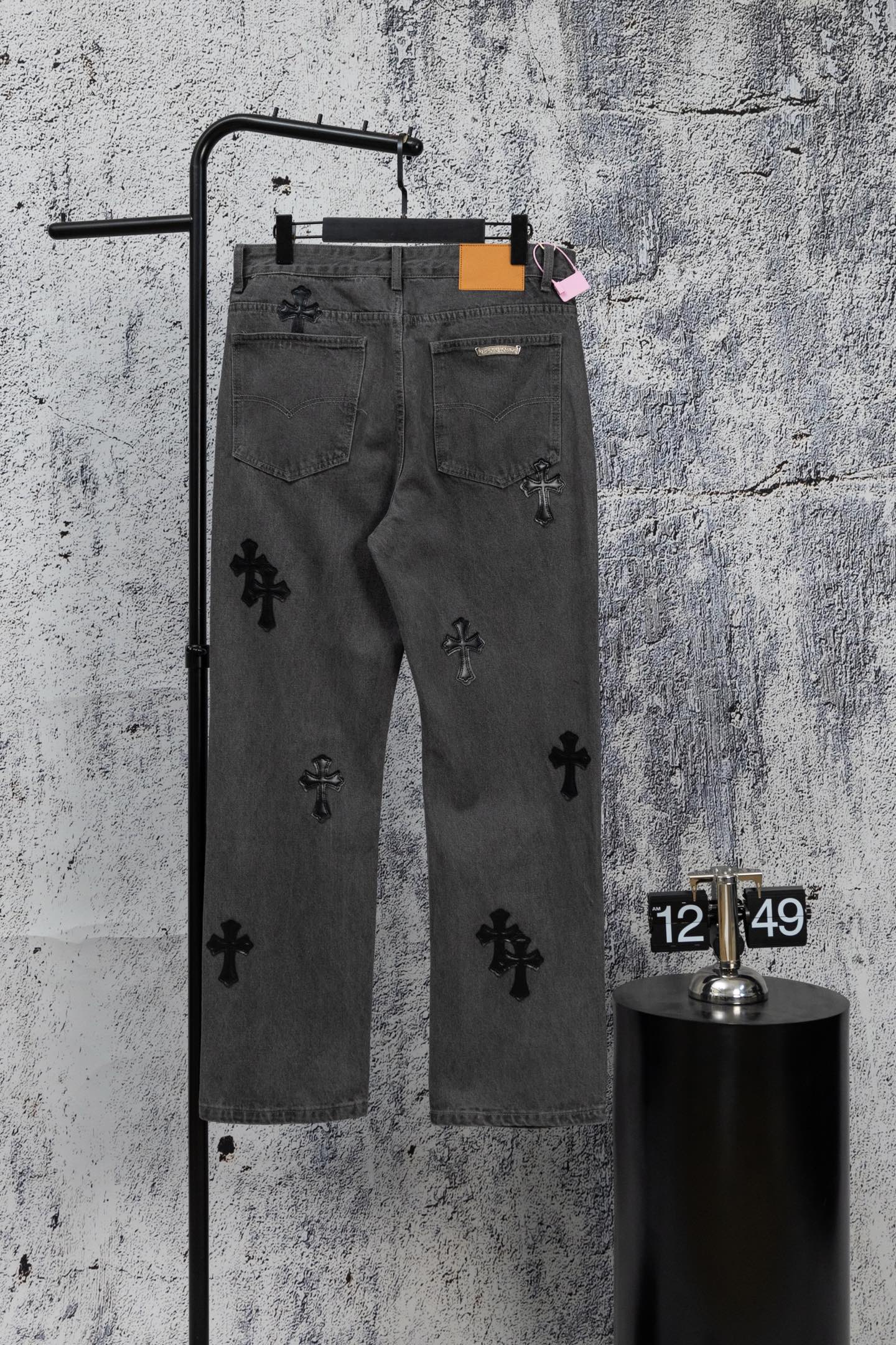 Dark gray denim pants with scattered black cross appliques and belt loops