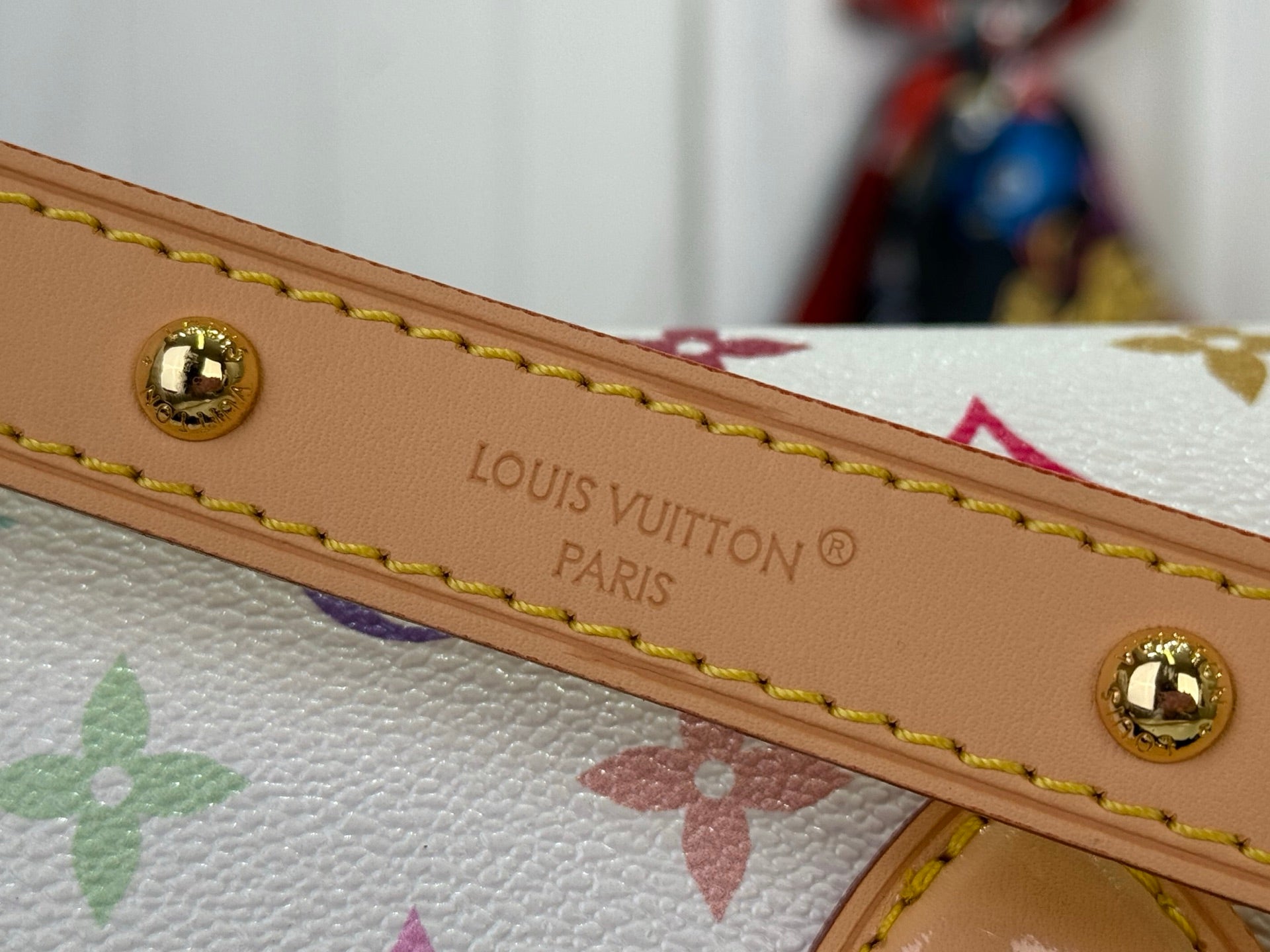 Louis Vuitton strap with “Louis Vuitton Paris” text and gold-tone studs on tan leather