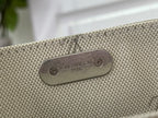 Rectangular metal logo plaque reading Louis Vuitton Paris on tan textured fabric