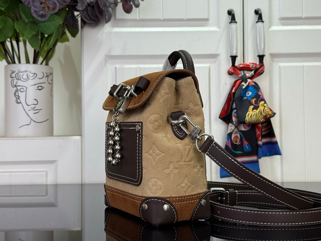 Tan and brown mini backpack with top handle, patterned front panel, and chain detail