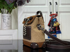 Tan and brown mini backpack with top handle, patterned front panel, and chain detail