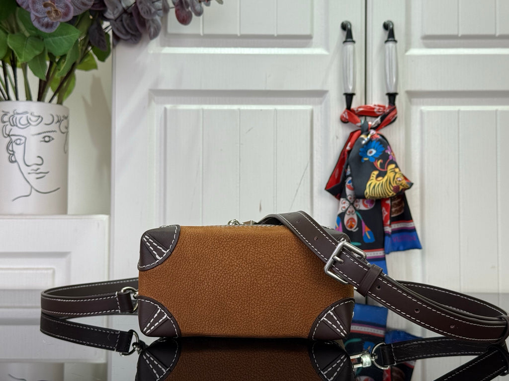 Brown mini backpack with curved flap, dark shoulder strap, and metal buckle hardware