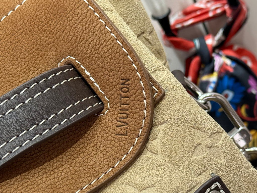 Brown leather patch with engraved oval text and stitched pocket detail on handbag