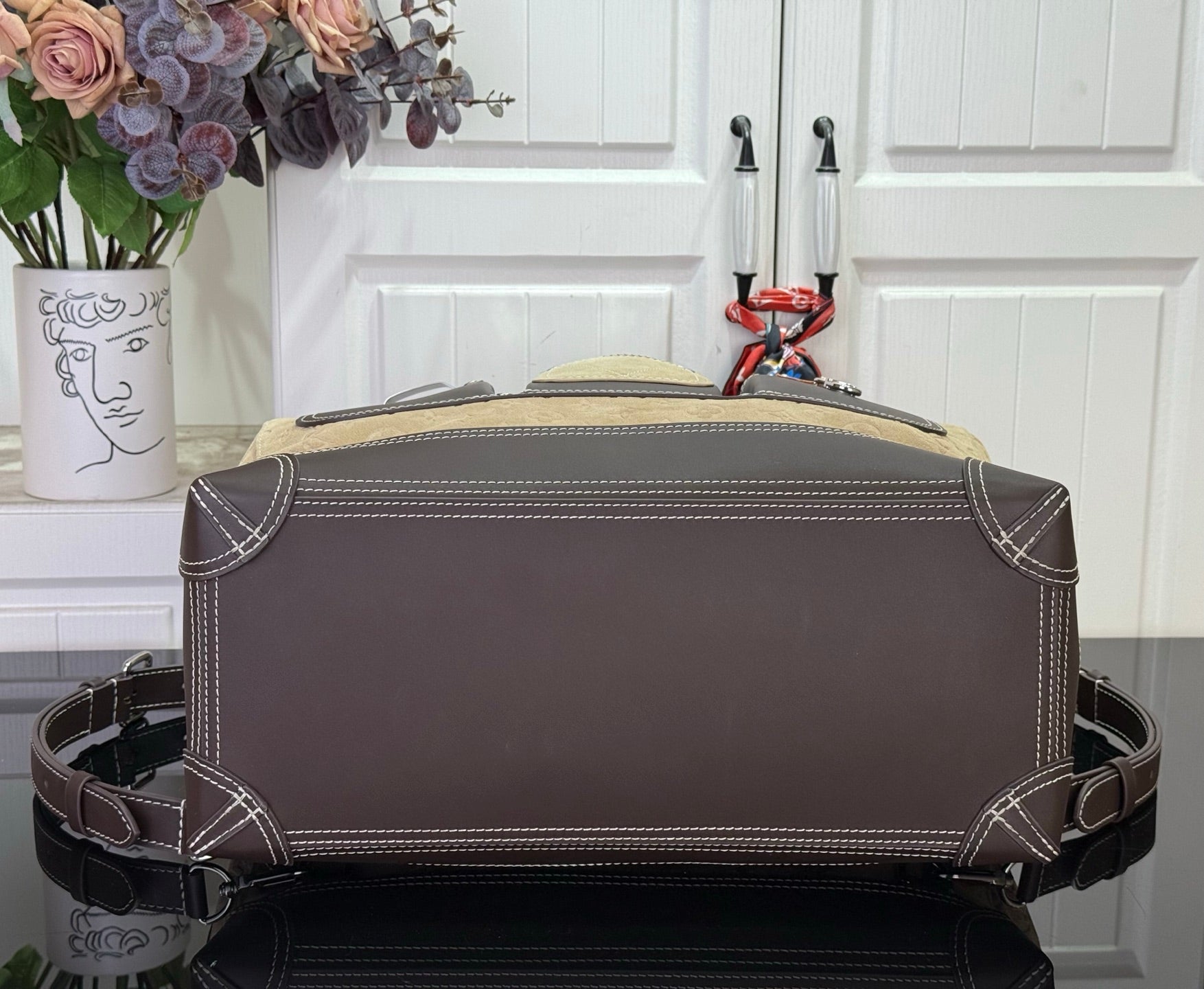 Louis Vuitton handbag back view with dark top panel and corner stitching, brown.