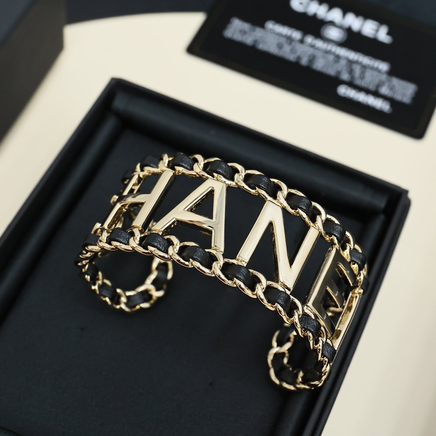 Gold-tone chain bracelet with CHANEL letter centerpiece and black enamel link borders