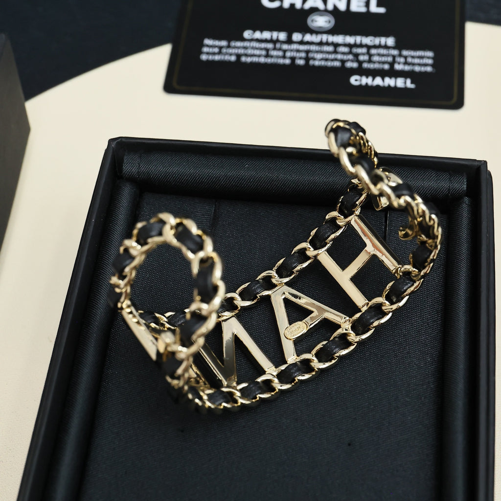 Gold-tone chain bracelet with CHANEL letter links on black bracelet cushion