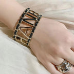 Gold-tone chain bracelet with CHANEL letter design worn on wrist