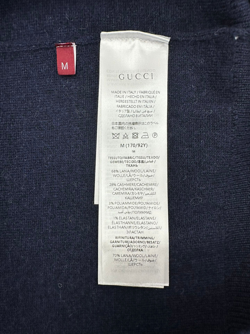 Size label and care tag inside a navy GG monogram knit sweater