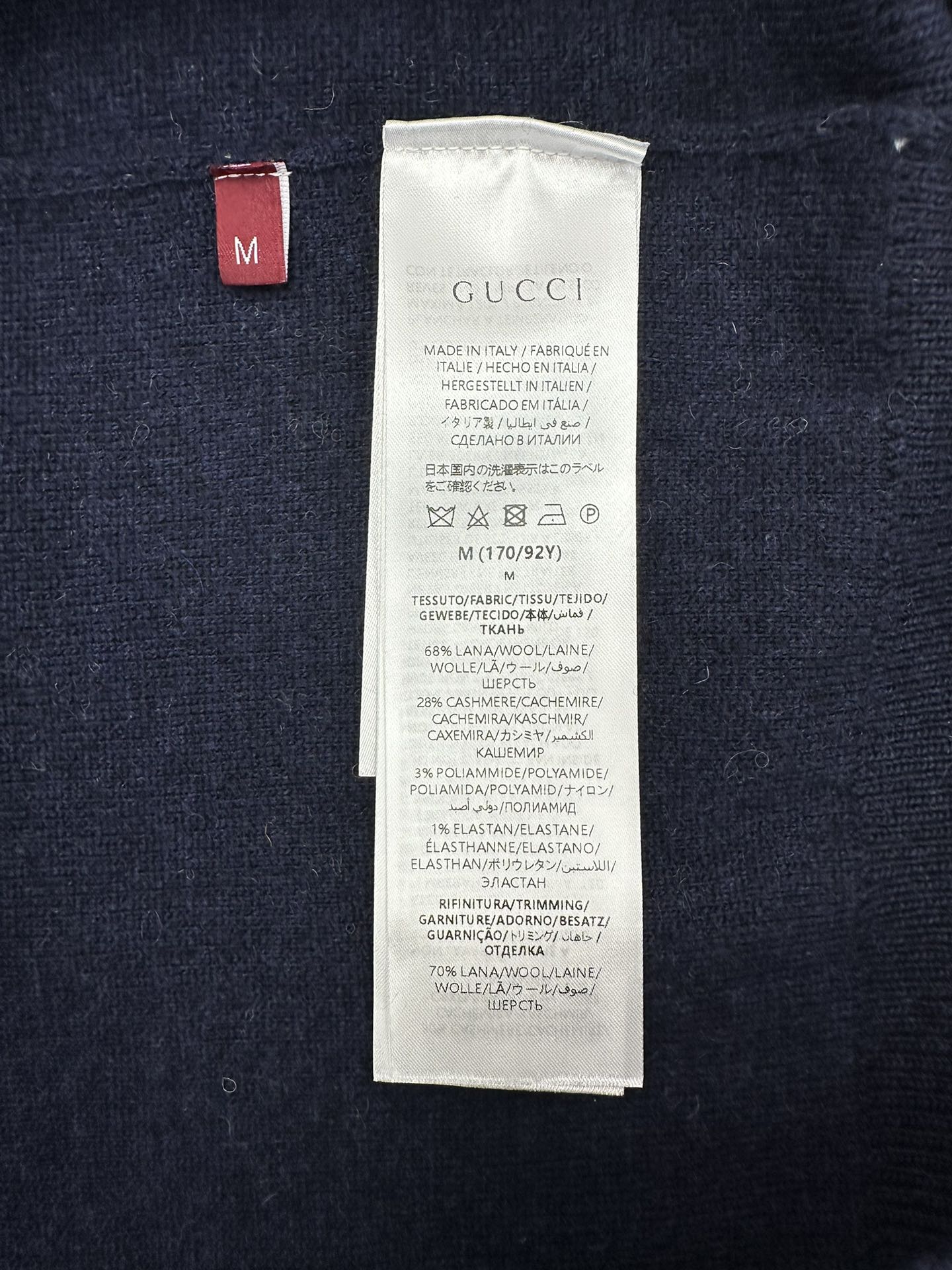 Size label and care tag inside a navy GG monogram knit sweater