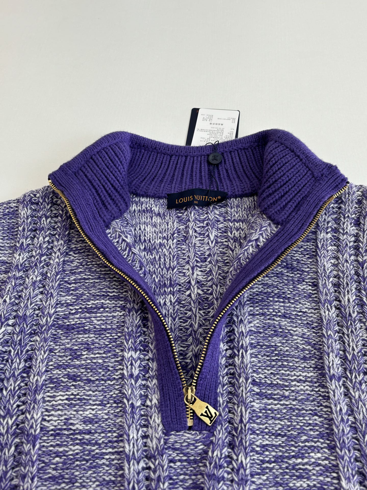 Quarter-zip knit sweater neckline with ribbed purple collar and visible zipper pull charm