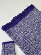 Knit sweater sleeve and hem with heathered blue texture and purple fringe trim
