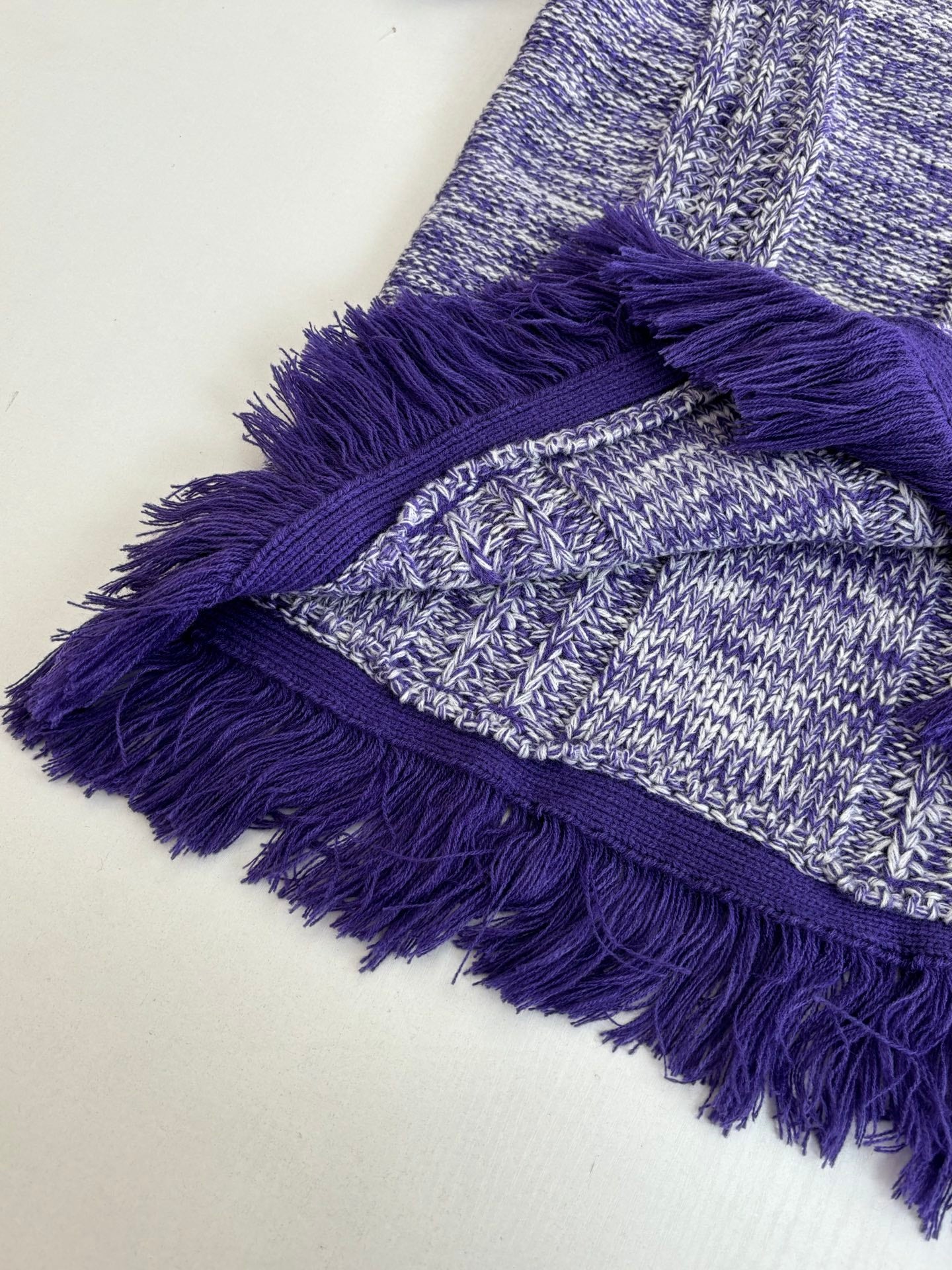 Knit sweater detail with layered purple fringe and heathered blue stitch texture